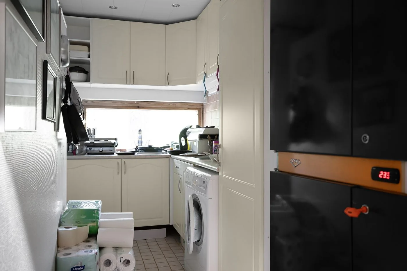 A compact and modern kitchen with laundry appliances, featuring white cabinets and natural light.