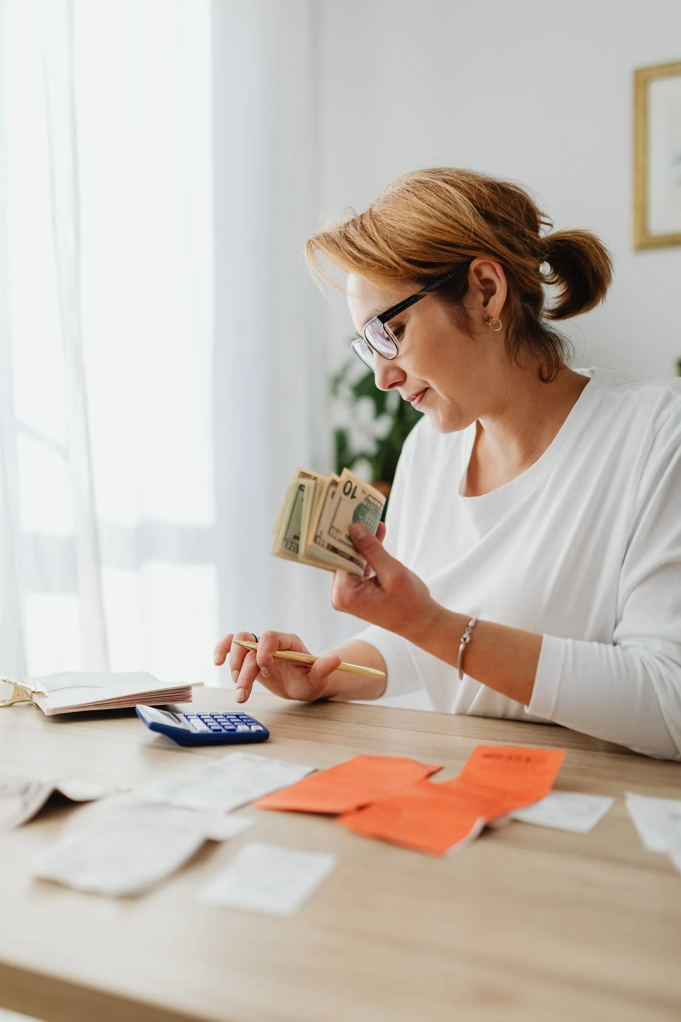 Woman counting cash and planning budget at indoor home office setting.