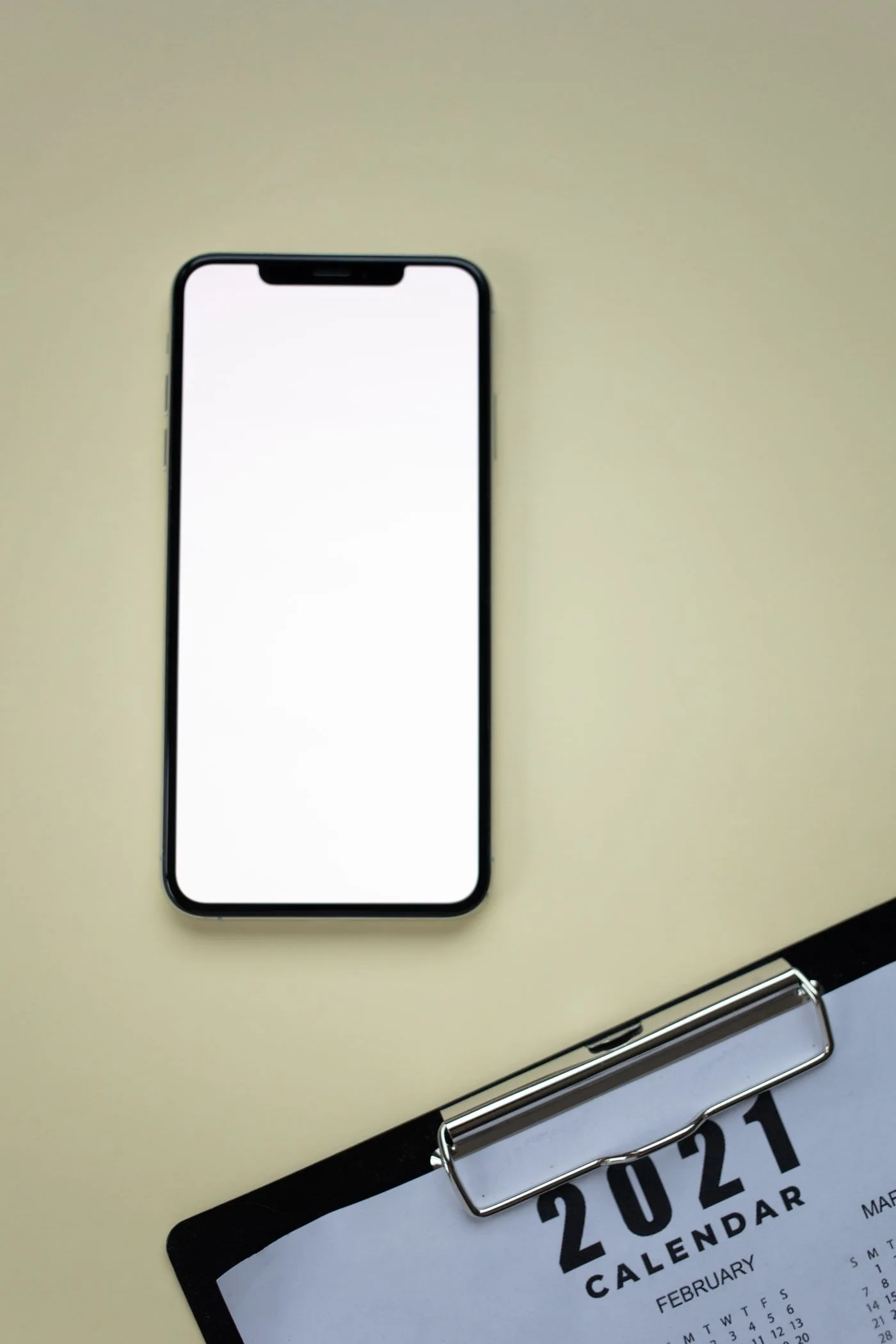 Top view of a smartphone and a 2021 calendar on a green surface.