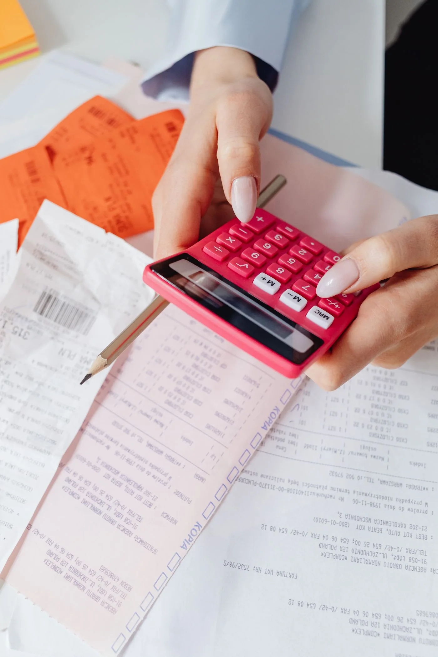 Image: Free Hands using a red calculator surrounded by financial documents and receipts, symbolizing financial management.
