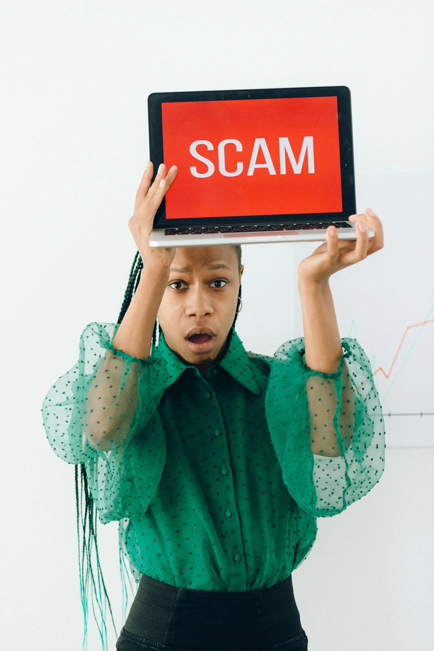 woman holding laptop displaying a scam alert, highlighting online fraud.