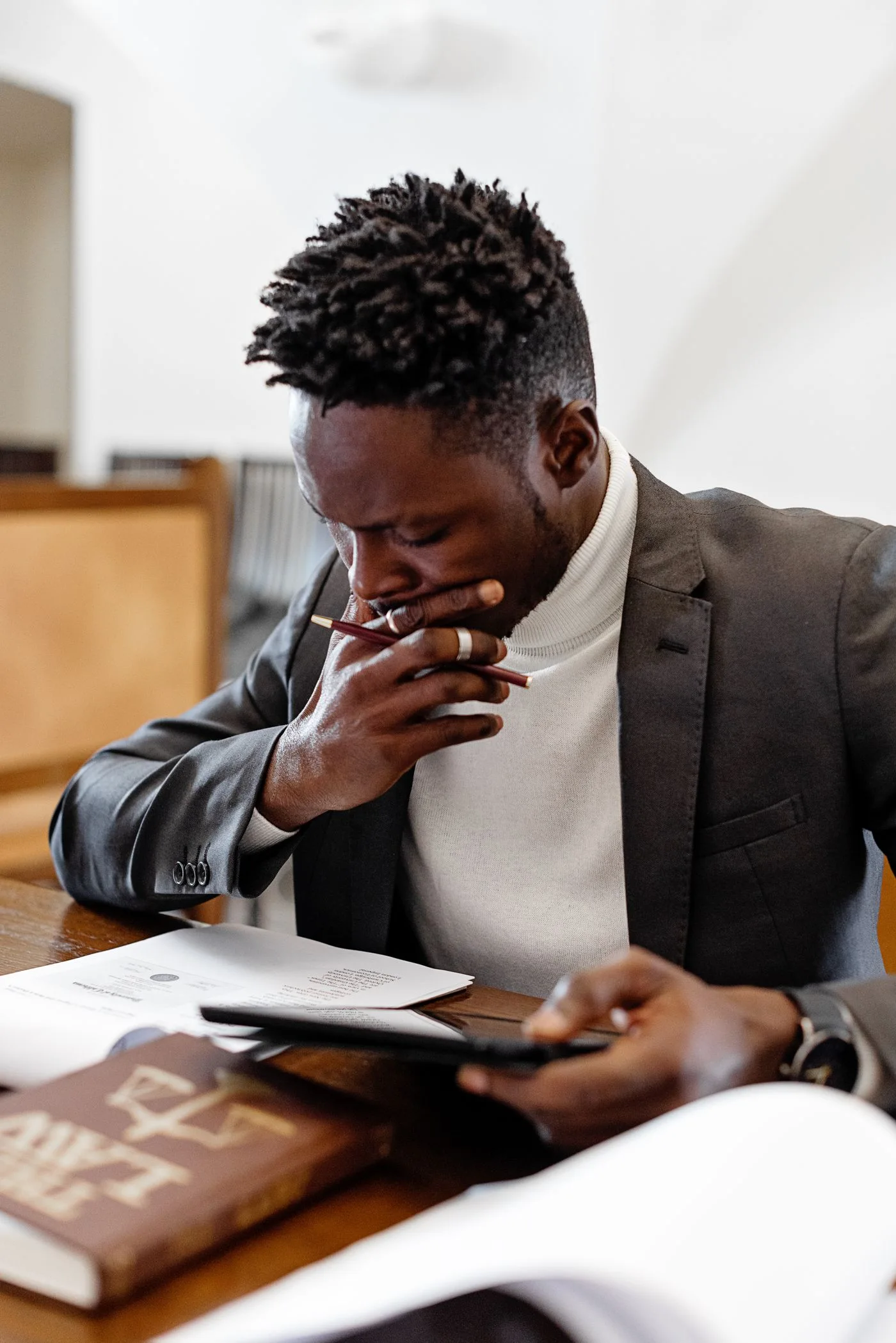 Focused adult man deeply engrossed in reading documents at a desk, using a tablet.