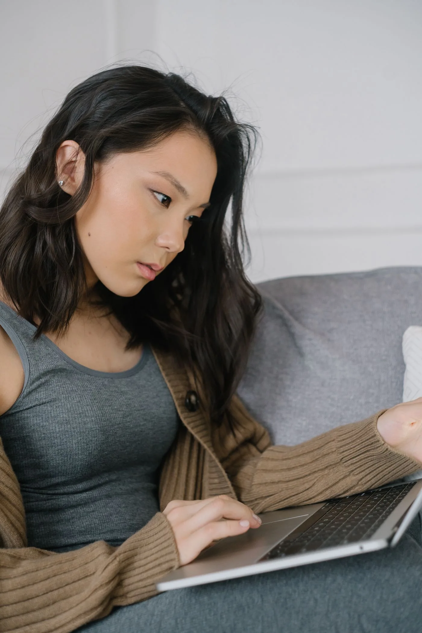 woman intently working on a laptop while relaxing on a cozy sofa.
